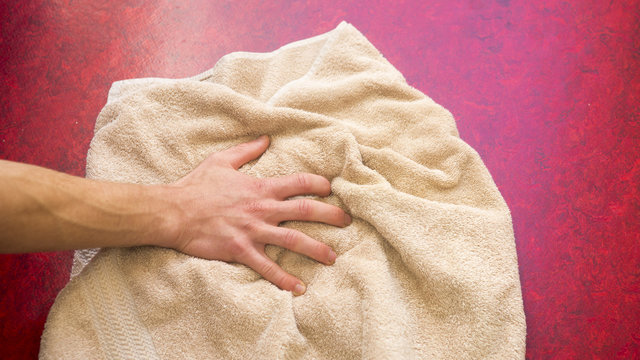 Closeup Of Hand And Beige Towel On Floor