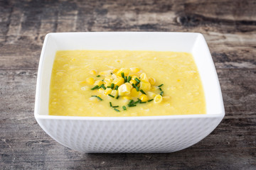 Corn soup in white bowl on wooden table

