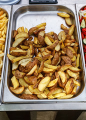 Steel container with roasted potato wedges, country stile potatoes