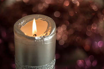 single lit candle - silver color - dark bokeh background
