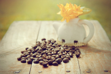 Obraz na płótnie Canvas Coffee beans on grunge wood background with Ixora flower pot and
