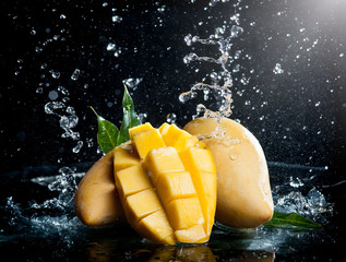 Naklejka na ściany i meble Mango splashing over clear water on black background