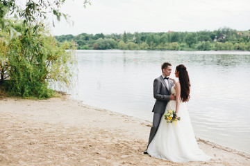Groom embracing bride on the river bank