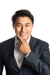 A well dressed businessman in a blue suit and white shirt, standing against a white background smiling towards camera.