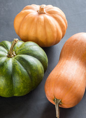 Three pumpkins on the dark wooden background