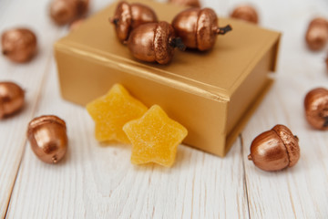 Christmas composition.Golden present box and golden acorns.White wooden table,jujube stars.Selective focus
