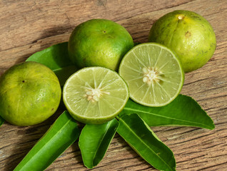 Fresh juicy lemon fruit sliced on wood background and lemon leaves.