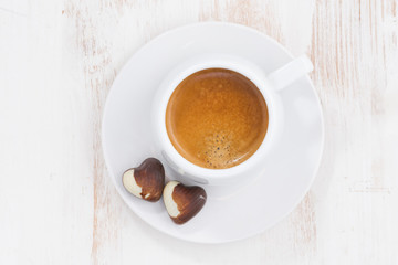chocolate hearts and espresso on white table, top view