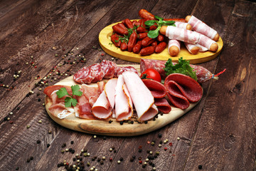 Food tray with delicious salami, pieces of sliced ham, sausage, tomatoes, salad and vegetable - Meat platter with selection
