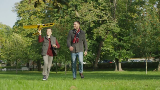 Father and Son are Running in with Model Airplane in the Park.  Shot on RED Cinema Camera in 4K (UHD)