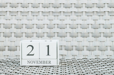Closeup surface white wooden calendar with black 21 november word on blurred weave wood chair textured background with copy space , selective focus at the calendar