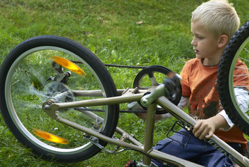 Preteen boy repair bicycle  on the summer sunny park
