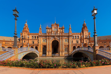 Fototapeta na wymiar Spain Square or Plaza de Espana in Seville in the sunny summer day, Andalusia, Spain. Flower beds, bridges and channel in the foreground