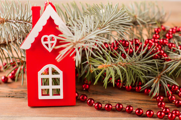 Toy house stands near a Christmas tree.