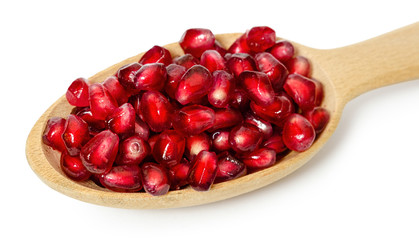wooden spoon full of pomegranate seeds, isolated on white background