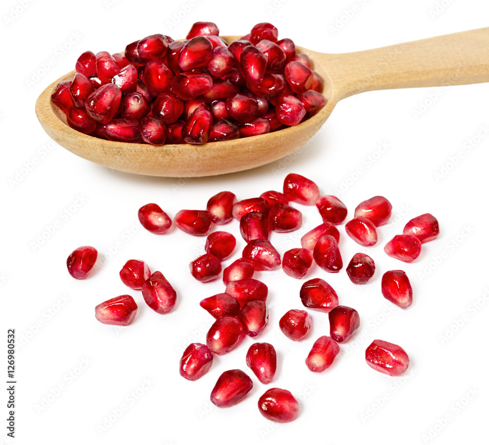 Wall mural wooden spoon full of pomegranate seeds, isolated on white background