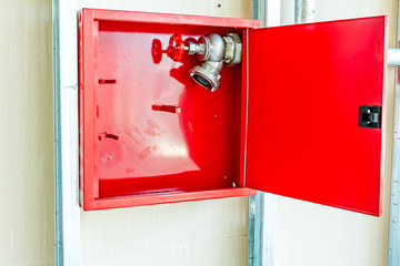 Red box with fire hydrant is built in an unfinished plaster wall