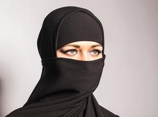 Young woman wearing niqab on background