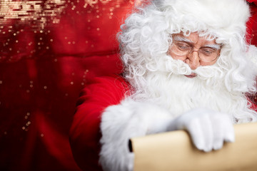 Portrait of happy Santa Claus holding Christmas letter 