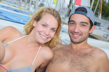 cheerful couple laying next to sailboats