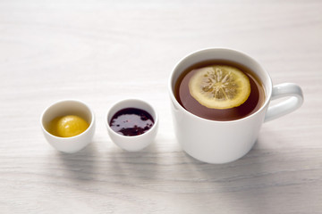 white mug with tea and lemon , jam  honey