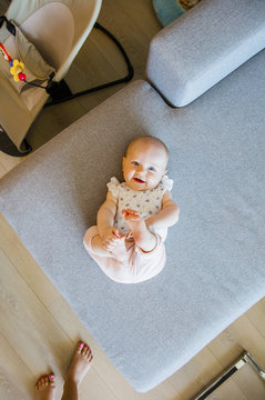 Cute baby girl with blue eyes playing on the sofa