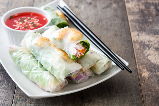 Vietnamese rolls with vegetables, rice noodles and prawns with sweet chili sauce  on wooden background
