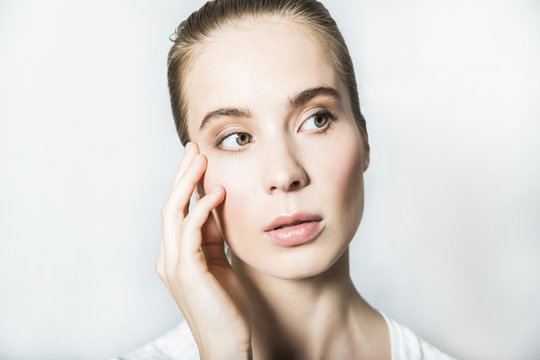 Portrait of young blonde beautiful girl with hand on face