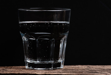glass of clear water on the wooden textural background