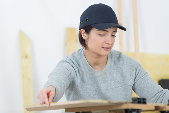 portrait of happy female woodworker drafting new project at workshop