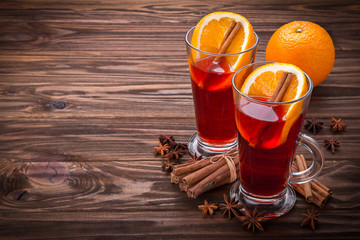 Glass with mulled wine, spices and fruits on wooden background