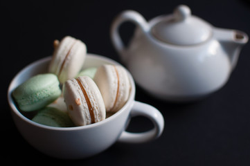 cup of tea with french macaroon on dark background.