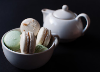 cup of tea with french macaroon on dark background.