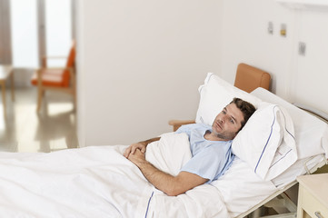 young patient man lying at hospital bed resting tired looking sad and depressed worried