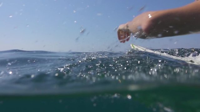 SLOW MOTION: Athletic surfer man paddling out on surf in open water ocean