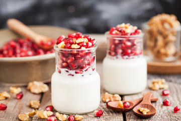 Fresh yogurt with pomegranate seeds and walnut in a glass jars