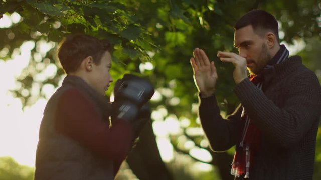 Father Teaches his Son Boxing with Gloves. Recreactional Activities in the Autumnt Park. Shot on RED Cinema Camera in 4K (UHD) 