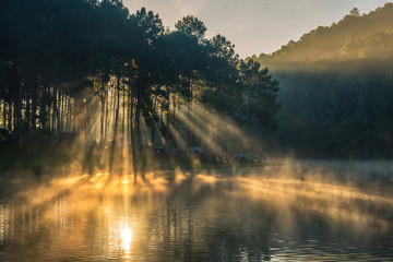 Morning in Pang Ung Lake,North of Thailand, is a tourist place where people come to vacation in the winter. Because of the large reservoir The cold causes steam to rise above the surface. - obrazy, fototapety, plakaty