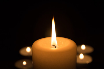 Kerze brennt vor Teelichtern