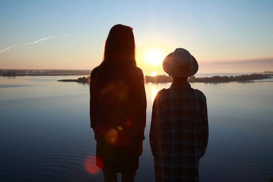 мальчик и девочка смотрят на восход солнца