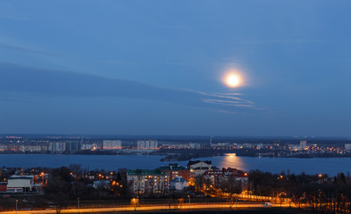 View of early moon in blue evening sky with reflection in the river. Background