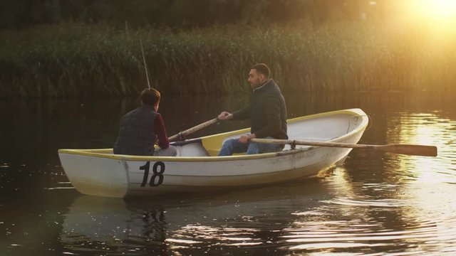 Father and Son on the Boat. Father is Rowing while Son fishes. Shot on RED Cinema Camera in 4K (UHD) 