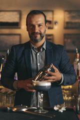 Barman is making cocktail at night club.
