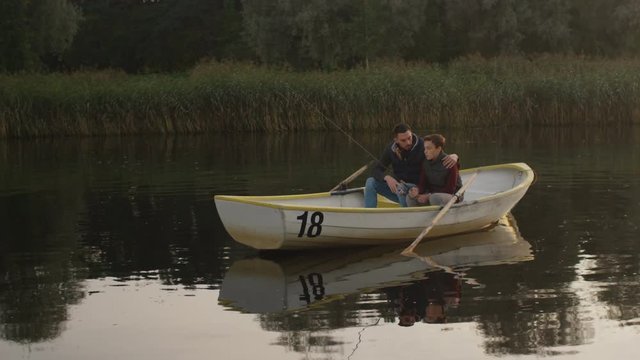 Father and Son are Sitting in the Boat and Fishing. Shot on RED Cinema Camera in 4K (UHD) 