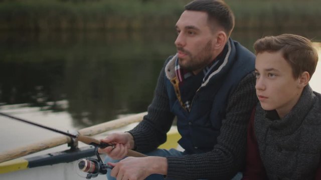 Father Teaches His Son Fishing. Both are Sitting in the Boat. Shot on RED Cinema Camera in 4K (UHD) 
