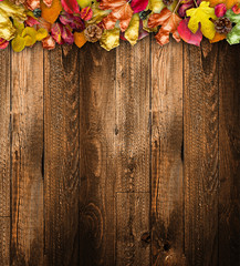 Autumn Leaves over a Natural Dark Wooden background. Old dirty wood tables or parquet with knots and holes and aged partculars.