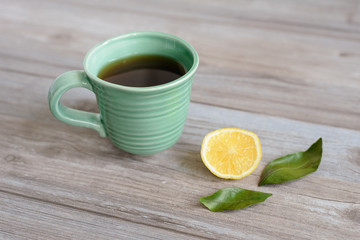 Obraz na płótnie Canvas cup or mug of black tea with green leaves and lemon