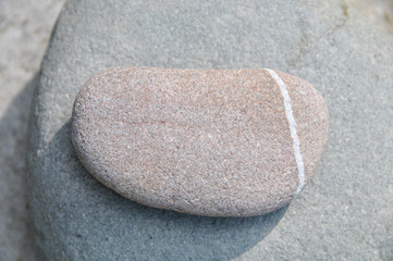 Fototapeta na wymiar Flacher Stein mit weissem Streifen auf grossem stein