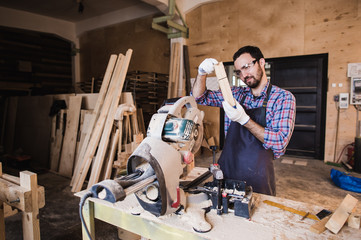 Carpenter working on an electric buzz saw cutting some boards, he is wearing safety glasses