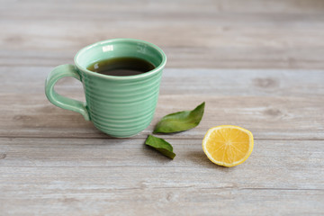 cup or mug of black tea with green leaves and lemon